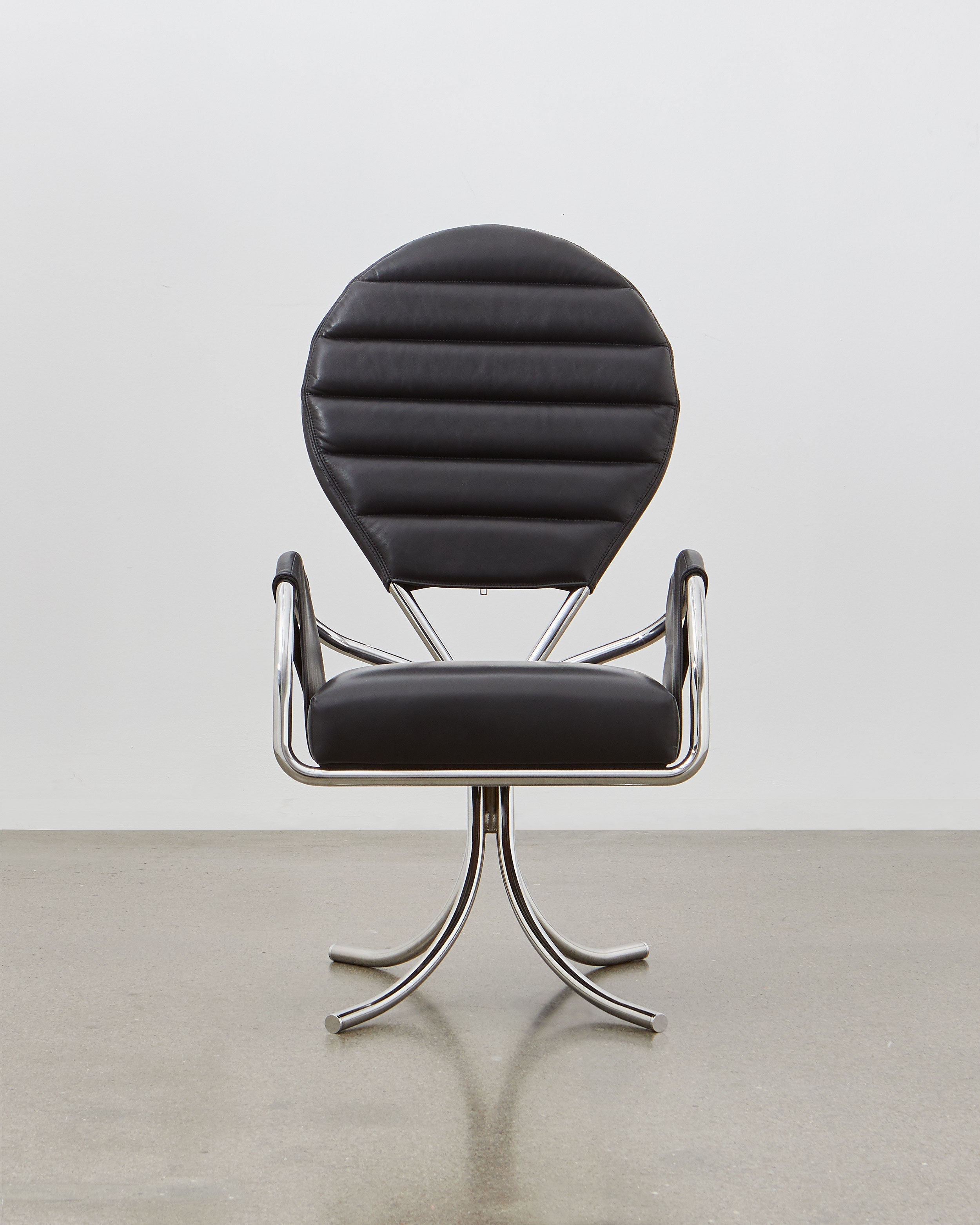 A black leather upholstered chair with a chrome-plated steel frame and a rounded backrest, designed in a modernist style.