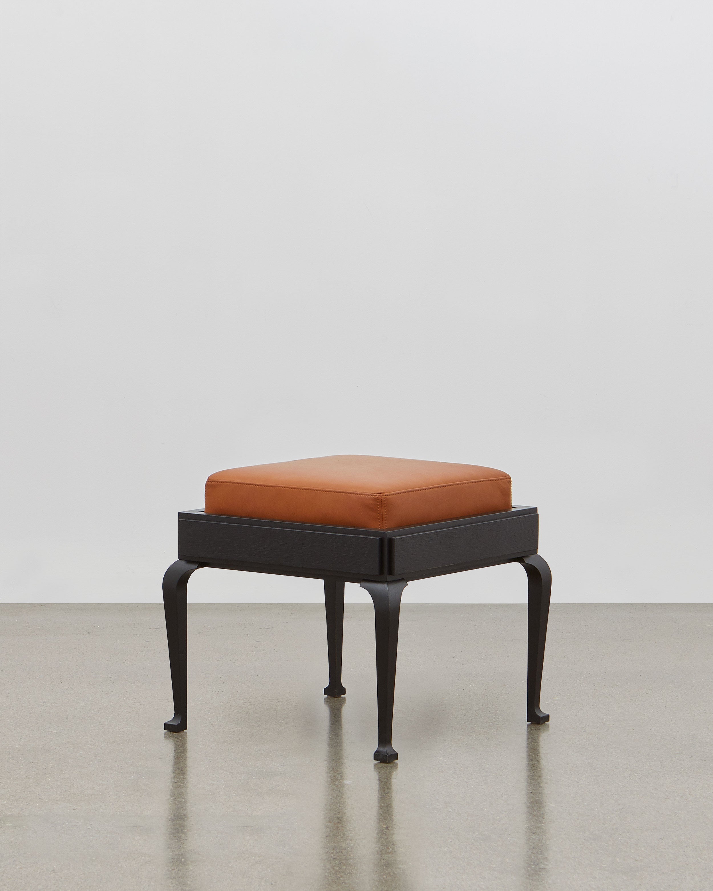 PH Stool by Poul Henningsen, Danish design classic (1920) A walnut upholstered stool standing on four angled black wooden legs.