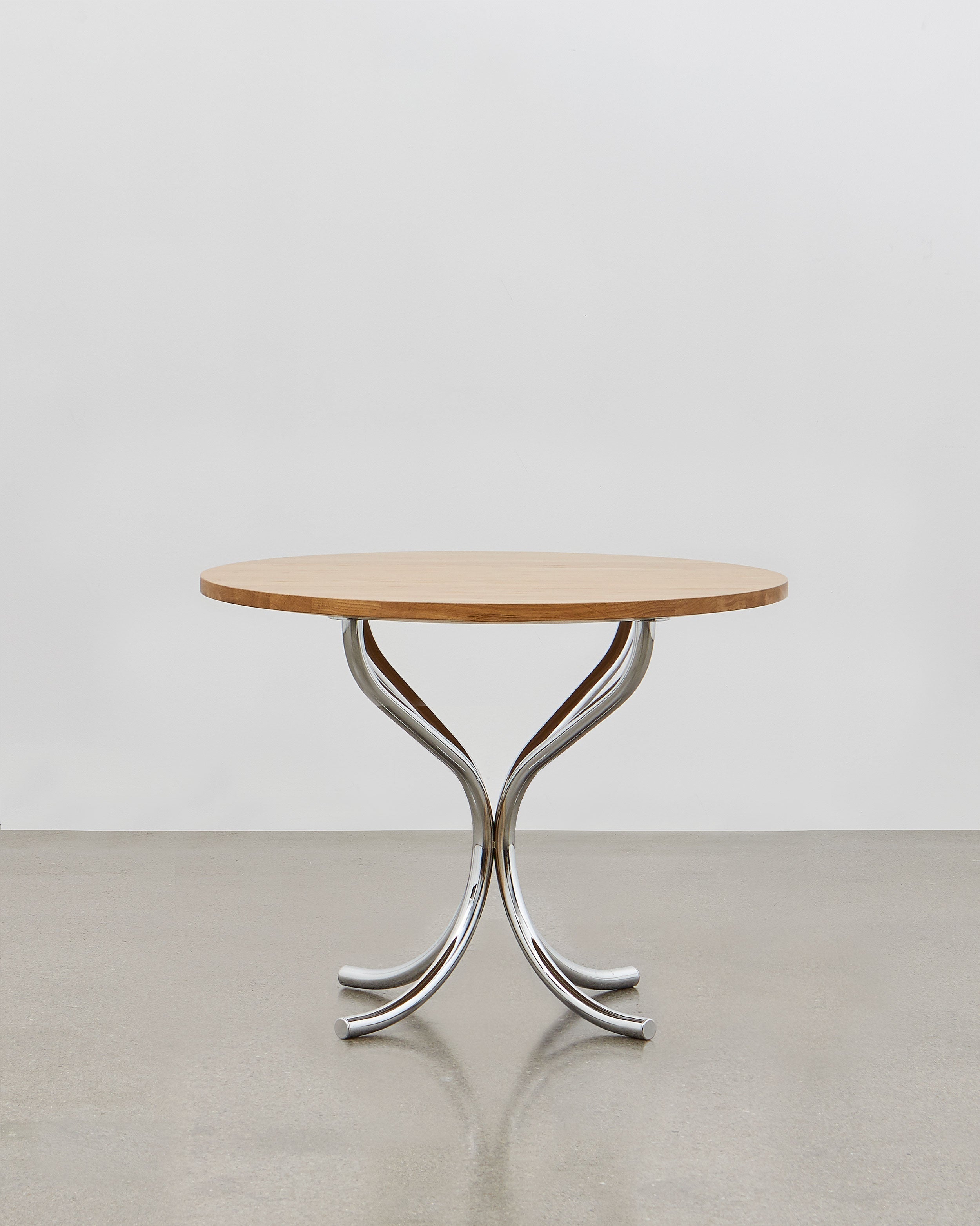 A round wooden lounge table with chrome metal legs, designed by Poul Henningsen.