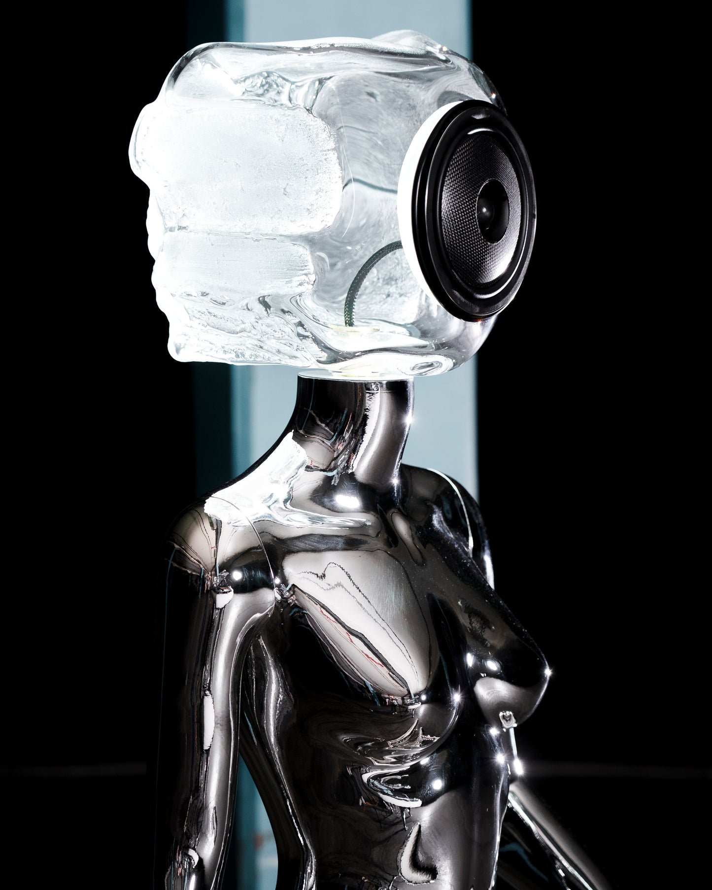 Audiomus is a audio design a chrome metallic sculpture of a seated figure on a concrete base with build in subwoofer and a mouth-blown glass sphere with light and the speaker driver built in 
