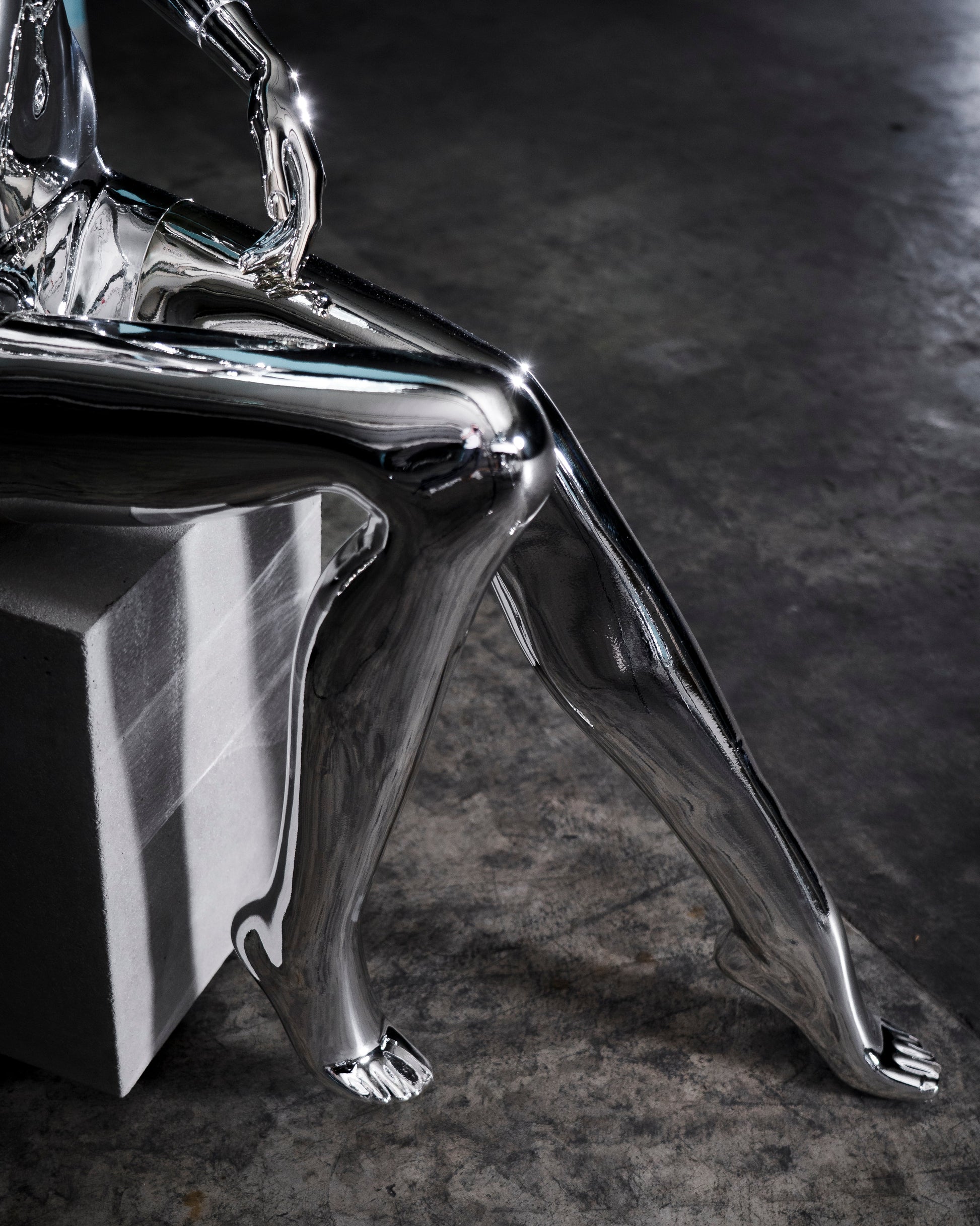 Audiomus is a audio design a chrome metallic sculpture of a seated figure on a concrete base with build in subwoofer and a mouth-blown glass sphere with light and the speaker driver built in 
