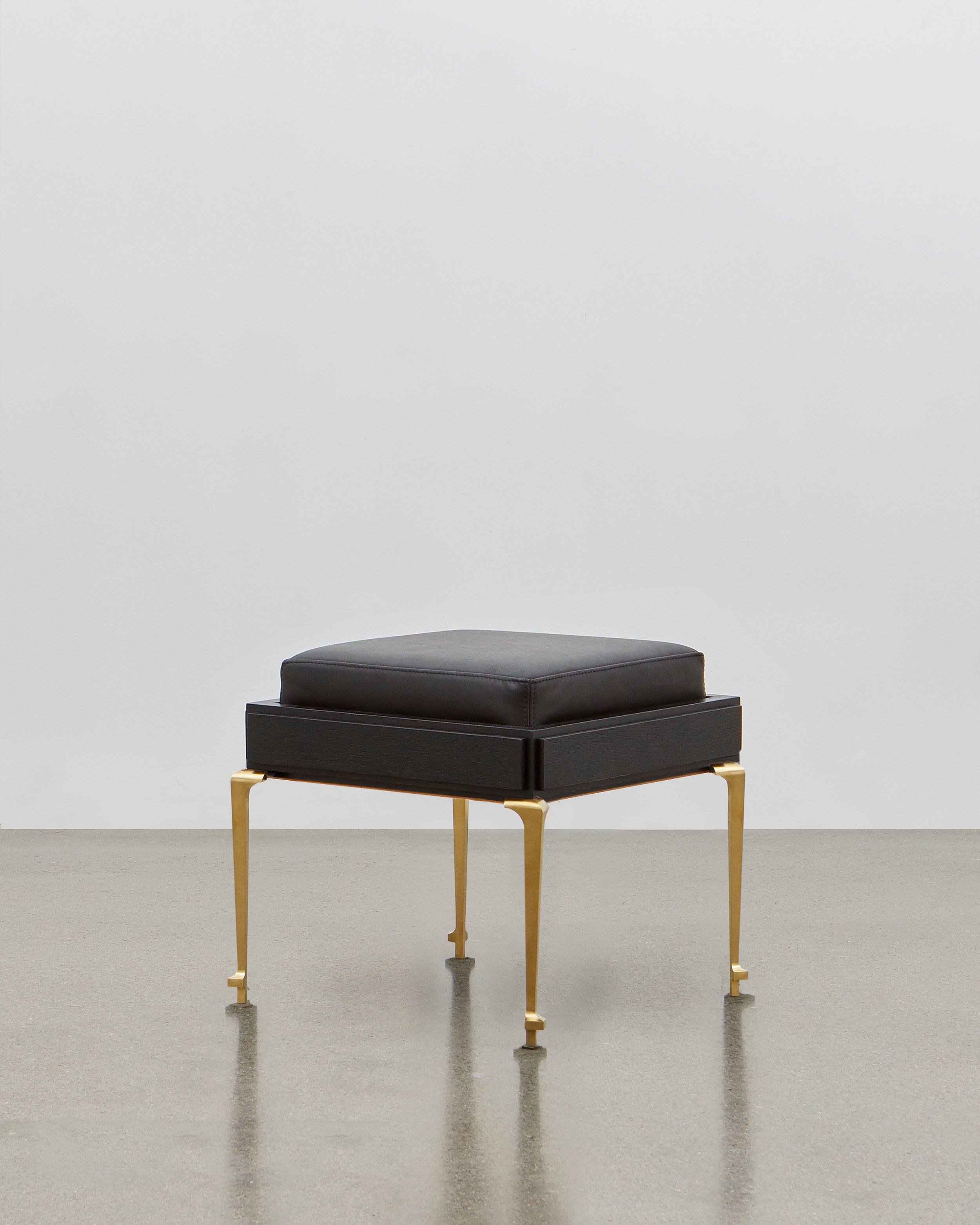 PH Stool by Poul Henningsen, Danish design classic (1920) A black upholstered stool standing on four brass legs
