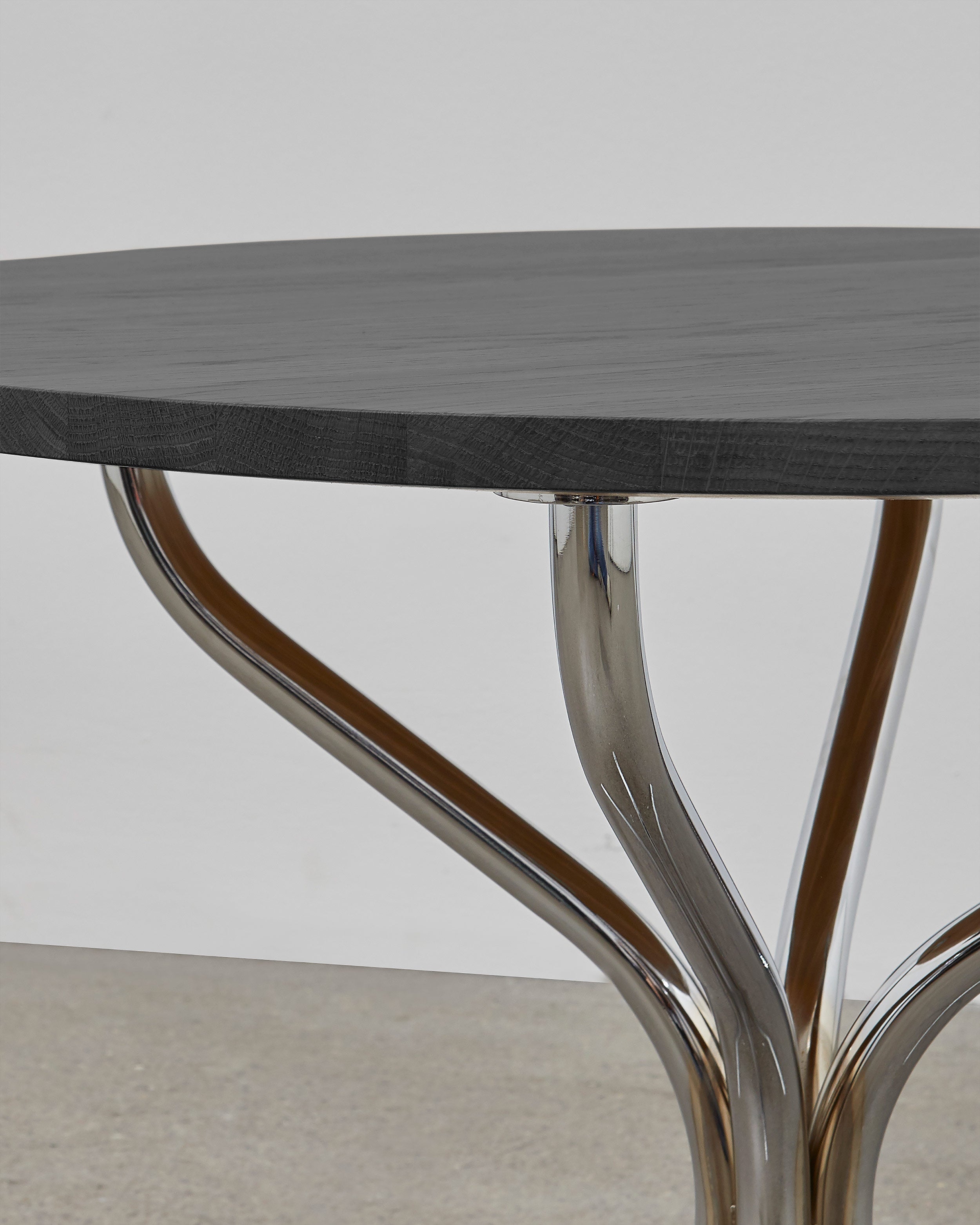 A round wooden lounge table with chrome metal legs, designed by Poul Henningsen.