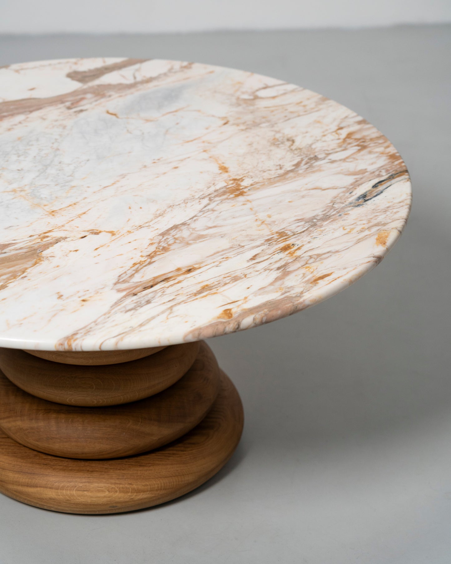 Spine Coffee Table pairs an architectural base of stacked solid-wood rings with a polished stone top, Wooden table with marble top 